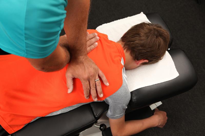 Chiropractor performing spinal adjustment in Vista treatment room