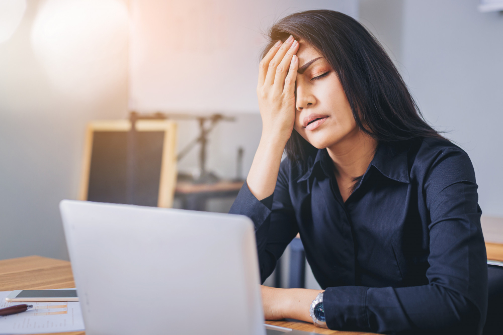 Woman shielding face with hand from light due to migraine