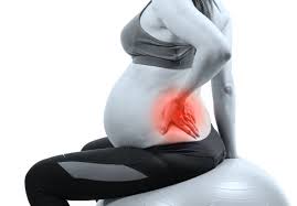 Pregnant woman holding lower back in discomfort