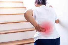 Person holding lower back in pain while standing